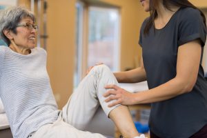 A physical therapist talks with her elderly patient in a clinic about managing cancer pain