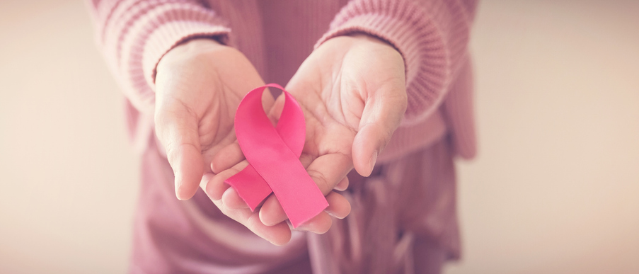 Woman hands holding pink ribbon for breast cancer awareness